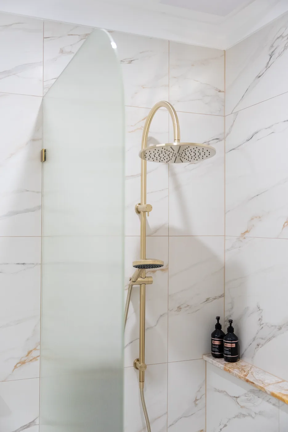 Walk-in shower with brushed brass rainfall head and marble tiling