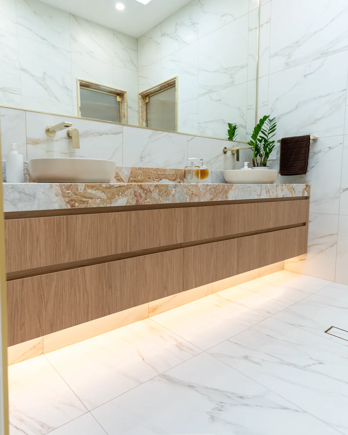 Floating timber vanity with twin stone basins and gold-veined benchtop