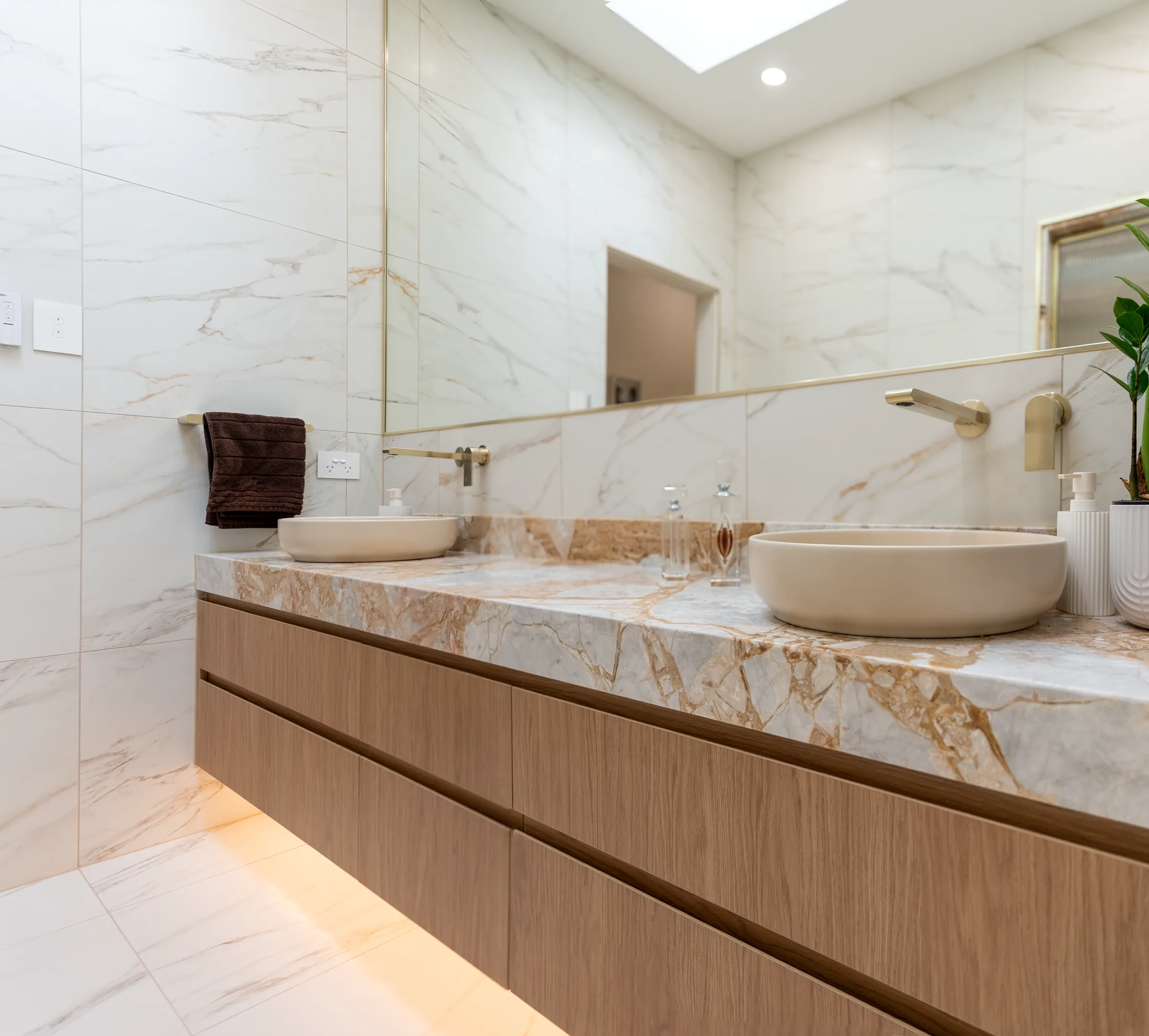 Premium Adelaide bathroom renovation with gold-veined stone vanity, twin stone basins and brushed brass tapware by Package Deal Bathrooms