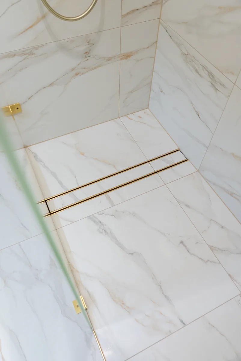 Tiled shower floor with linear brass drain and correct falls